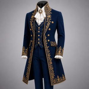 May include: A deep blue long coat and matching vest featuring intricate gold floral embroidery along the edges. The ensemble includes a white ruffled cravat with a central brooch, gold-toned buttons, and white ruffled cuffs at the sleeves.