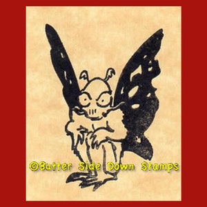 Könnte beinhalten: Schwarz-weiß-Illustration eines geflügelten Wesens, das einem Schmetterling ähnelt, mit einem schädelartigen Gesicht. Das Wesen sitzt mit ausgebreiteten Flügeln. Das Bild stammt von Butter Side Down Stamps.