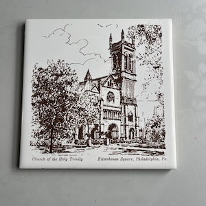May include: Square ceramic tile featuring a brown illustration of the Church of the Holy Trinity in Rittenhouse Square, Philadelphia, PA. The image depicts the church building surrounded by trees and clouds, with text at the bottom.