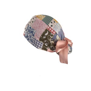 May include: A patchwork patterned cap with a variety of fabric patterns in shades of blue, pink, green, and yellow. The cap is tied with a large, light pink satin bow.