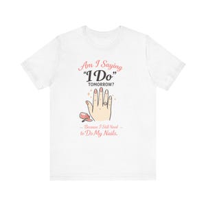 Könnte beinhalten: Weißes T-Shirt mit einem grafischen Design. Das Design zeigt eine Hand mit einem Ring, Nagellack und dem Text "Am I Saying 'I Do' Tomorrow? Because I Still Need to Do My Nails."