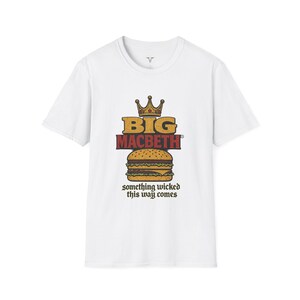 Puede incluir: Camiseta blanca con un gráfico de hamburguesa y el texto "BIG MACBETH" arriba y "something wicked this way comes" abajo. La hamburguesa es marrón y amarilla, y el texto es de estilo vintage.