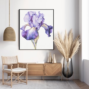 Peut inclure: Une impression encadrée à l'aquarelle d'une fleur d'iris violette. La fleur a des pétales superposés dans des tons de violet et de lavande, avec une tige jaune. L'œuvre est exposée sur un mur blanc, au-dessus d'un meuble en bois.