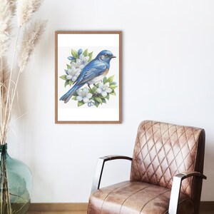 May include: A framed watercolour print depicting a bluebird on a flowering branch. The bird has blue and brown feathers, and the flowers are white with green leaves. The frame is made of wood.