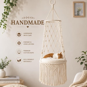 Puede incluir: Una cama colgante para gatos de macramé color crema con un diseño de cuerda en forma de diamante, una base circular con flecos largos y un cojín suave. El texto dice: HANDMADE, HANDMADE WITH CARE, DURABLE & LONG LASTING, PREMIUM COTTON ROPE, ECO-FRIENDLY MATERIALS.