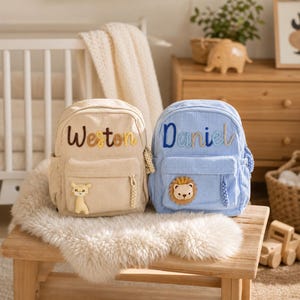 Peut inclure: Deux sacs à dos en velours côtelé, l'un beige avec le prénom Weston et un écusson girafe, l'autre bleu clair avec le prénom Daniel et un écusson lion. Les deux sacs ont des poches avant zippées, des poches latérales et des tirettes tressées.