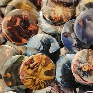 May include: A collection of circular pin-back buttons featuring various colorful illustrations of characters and action scenes from the Final Fantasy video game series, including depictions of Cloud Strife, Sephiroth, and a Moogle creature.