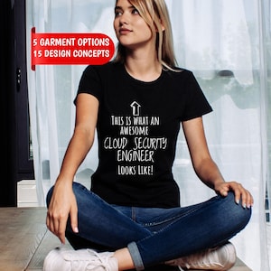 May include: A black short-sleeved t-shirt featuring a white upward-pointing arrow graphic and the text: This is what an awesome cloud security engineer looks like! A red banner in the upper left corner displays 5 garment options 15 design concepts.