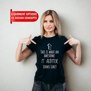 May include: A black short-sleeved t-shirt featuring a white upward-pointing arrow graphic and the text "THIS IS WHAT AN AWESOME IT AUDITOR LOOKS LIKE!" printed in a clean, sans-serif font on the front center of the garment.