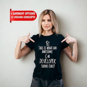 May include: A black short-sleeved t-shirt featuring a white upward-pointing arrow graphic and the text "THIS IS WHAT AN AWESOME C# DEVELOPER LOOKS LIKE!" printed on the front. The shirt has a crew neckline and a standard fit.