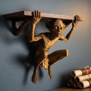 Puede incluir: Una estantería de pared única con una figura dorada que sostiene una estantería de madera. La figura está en cuclillas, con los brazos levantados para sostener la estantería. La estantería es de madera oscura. Decorativa y funcional.