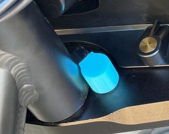 May include: A bright cyan, textured cylindrical knob is positioned on a black mechanical component. The knob features a ridged surface for grip and is situated next to a smooth black cylindrical frame member and a small brass-colored circular fastener.