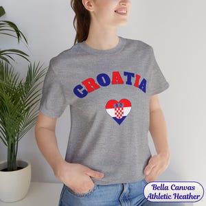 Model wearing a unisex Croatia shirt featuring a modern design with a heart-shaped Croatian flag detail on the chest. The look combines an aesthetic with a clean and minimal style. Suitable for both match days and everyday wear, this shirt offers a comfortable and versatile option for fans supporting Croatia, with a subtle yet distinctive expression of national pride.