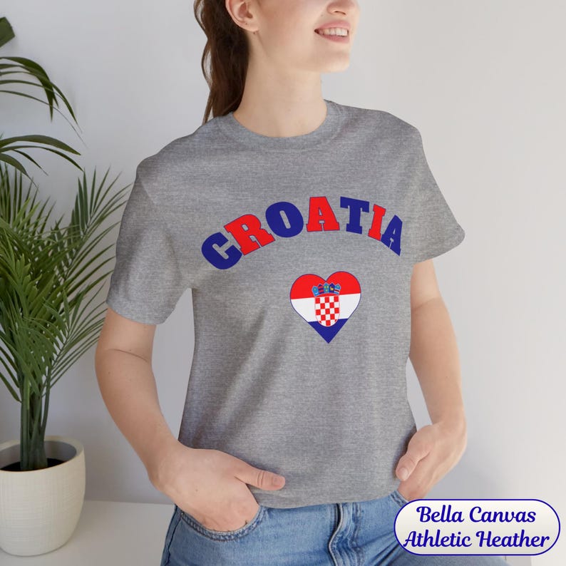 Model wearing a unisex Croatia shirt featuring a modern design with a heart-shaped Croatian flag detail on the chest. The look combines an aesthetic with a clean and minimal style. Suitable for both match days and everyday wear, this shirt offers a comfortable and versatile option for fans supporting Croatia, with a subtle yet distinctive expression of national pride.
