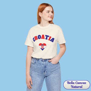 Model wearing a unisex Croatia shirt featuring a modern design with a heart-shaped Croatian flag detail on the chest. The look combines an aesthetic with a clean and minimal style. Suitable for both match days and everyday wear, this shirt offers a comfortable and versatile option for fans supporting Croatia, with a subtle yet distinctive expression of national pride.