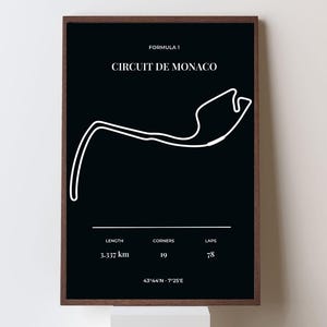 Op de afbeelding: A framed poster with a black background features the white outline of the Circuit de Monaco race track. The text at the top reads "FORMULA 1" and "CIRCUIT DE MONACO." Below, it lists the track's length as 3.337 km, 19 bochten, and 78 ronden.