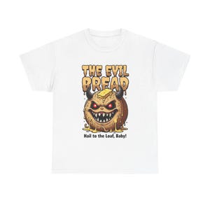 Puede incluir: Camiseta blanca con una ilustración de dibujos animados de una hogaza de pan con cuernos, dientes afilados y ojos rojos. El texto "THE EVIL BREAD" está encima del pan, y "Hail to the Loaf, Baby!" está debajo.