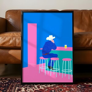 Könnte beinhalten: Gerahmter Kunstdruck mit einer stilisierten Illustration einer Person mit Cowboyhut an einer Bar. Das Kunstwerk verwendet eine lebendige Farbpalette aus Blau, Rosa und Grün. Die Person sitzt auf einem rosa Hocker, mit einem Getränk an der Bar.