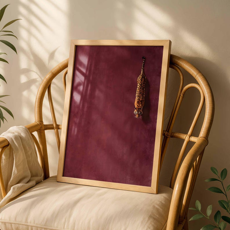 May include: A rectangular framed wall art piece featuring a deep burgundy background with a small, vertically oriented illustration of a tiger positioned in the upper right quadrant, encased in a light-toned wooden frame.