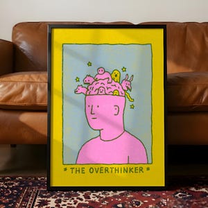 Pode incluir: Impressão artística emoldurada com uma figura rosa com a cabeça aberta cheia de criaturas de desenho animado. O fundo é azul claro com estrelas amarelas. A impressão tem uma borda amarela e o texto "THE OVERTHINKER" em preto.