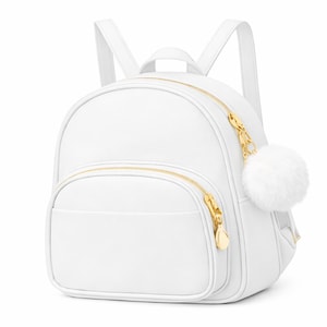 Puede incluir: Mochila blanca con cremalleras doradas y un pompón blanco y esponjoso. La mochila tiene forma redondeada con un bolsillo frontal y correas ajustables. Las cremalleras y la cadena son doradas.