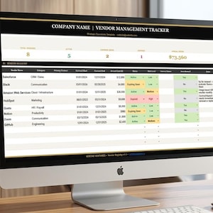 Op de afbeelding: Een desktopcomputer toont een leveranciersbeheer tracker. Het scherm toont een spreadsheet met gegevens, waaronder leveranciersnamen, categorieën en contractdetails. De computer staat op een houten bureau met planten en boeken op de achtergrond.