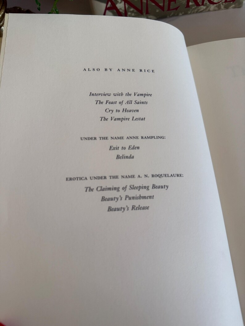 May include: Open book page with text listing works by Anne Rice, including "Interview with the Vampire," "The Feast of All Saints," and "Cry to Heaven." Also listed are works under the names Anne Rampling and A. N. Roquelaure.