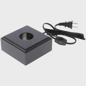 May include: A black, square display base with a circular indentation in the center. A black power cord with a switch and plug extends from the base. The base is made of a glossy, dark material.