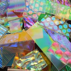 May include: Assortment of iridescent glass tiles in various shapes and sizes. The tiles have a rainbow sheen and are perfect for crafting projects.