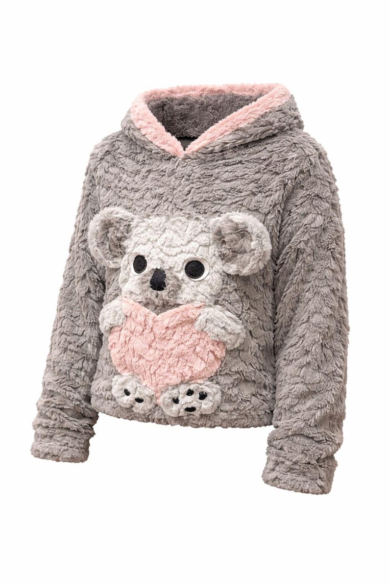 K&ouml;nnte beinhalten: Grauer Kapuzenpullover mit einem Pl&uuml;sch-Koala-B&auml;r-Design auf der Vorderseite. Der Koala hat gro&szlig;e schwarze Augen, eine schwarze Nase und h&auml;lt ein rosa Herz. Das Kapuzenfutter ist rosa.