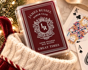 May include: A clear plastic case containing a deck of playing cards with a deep red label. The label features the text James Russel Poker Club, the initials JR inside a crest, Est. 2026, and the phrase Good Friends Bad Bluffs Great Times.