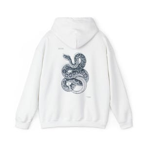 Op de afbeelding: Witte hoodie met een gedetailleerde illustratie van een opgerolde slang in grijstinten en zwart op de rug. Het slangenontwerp is gecentreerd en lijkt een gedetailleerde tekening te zijn. De hoodie heeft een capuchon en lange mouwen.
