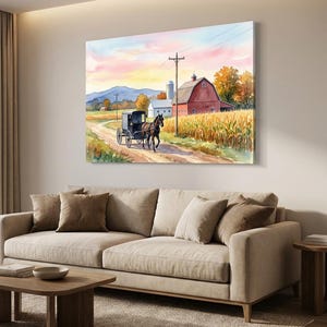 May include: A watercolour painting depicting a rural scene with a horse-drawn carriage on a dirt track. A red barn and silo are set against a sunset and hills. The artwork is displayed above a beige sofa in a living room.