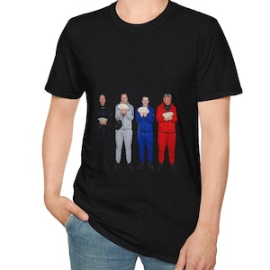 Puede incluir: Camiseta negra con una imagen de cuatro personas sosteniendo fajos de dinero. Visten chándales negros, grises, azules y rojos. La imagen tiene una calidad oscura y ligeramente granulada.