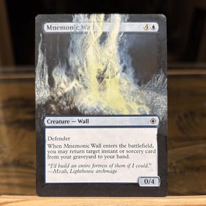 May include: A Magic: The Gathering card titled "Mnemonic Wall." The card features a fantasy illustration with a figure in a bright yellow light. The card text includes "Defender" and a quote from Mzali, Lighthouse archmage.