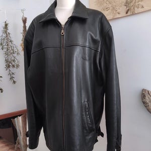 May include: Black leather jacket with a zip-up front, collar, and side pockets. The jacket has a small logo on the chest and adjustable cuffs. The jacket is displayed on a mannequin.