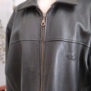 May include: Black leather jacket with a collared neckline and a full-length zipper. The jacket has a small logo on the chest and a classic design. The jacket is displayed on a mannequin.