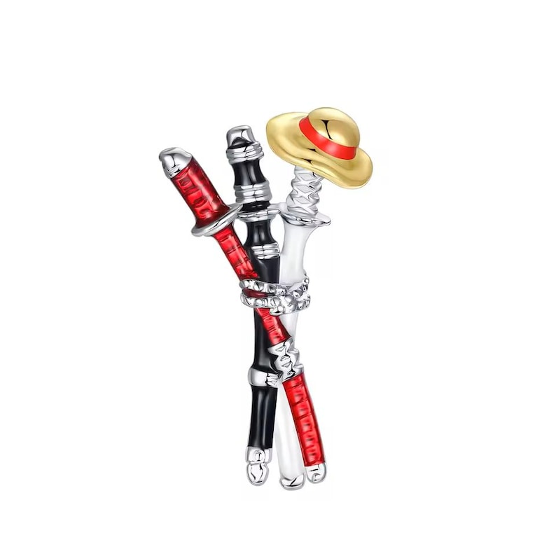 May include: A metal brooch featuring three crossed sword hilts in red, black, and white enamel, bound together by a silver-toned cord detail. A small, gold-coloured straw hat with a red band rests atop the white sword hilt, completing the design.