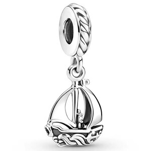 May include: A silver charm in the shape of a sailboat, featuring a polished metal finish with a rope-textured bail at the top. The sailboat design includes detailed sails and a hull decorated with wave-like patterns, creating a nautical aesthetic.