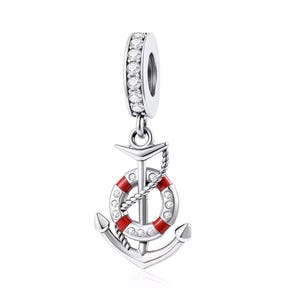 May include: A silver charm featuring a vertical anchor design with a red and white life preserver ring attached. The charm includes a bail encrusted with clear stones, and the life preserver ring is accented with small clear stones along its surface.
