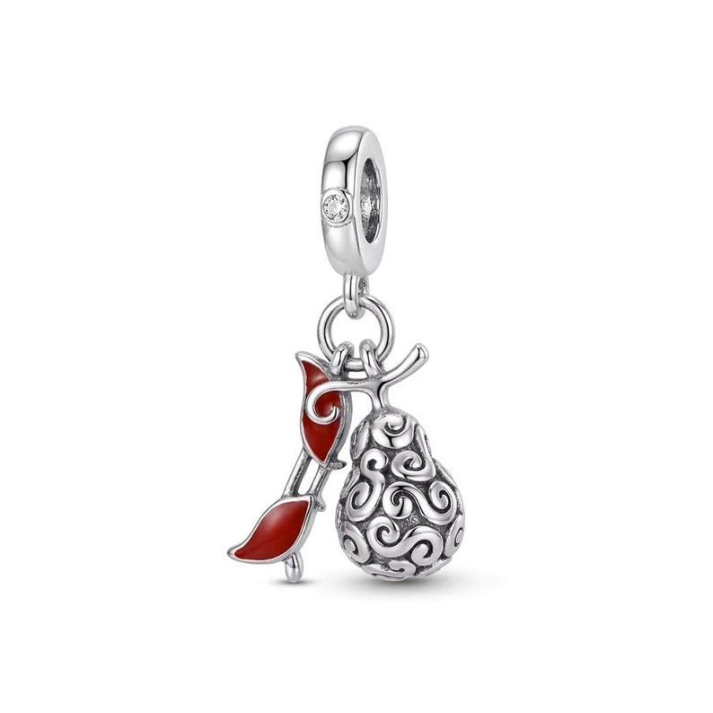 May include: A silver charm featuring a pear-shaped pendant with intricate swirling patterns and a separate curved element accented with glossy red enamel. The charm includes a small clear stone set into the top loop for attachment to a bracelet.