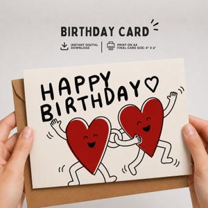 Puede incluir: Tarjeta de cumpleaños con las palabras "HAPPY BIRTHDAY" en negro, con dos personajes de corazón rojo con brazos y piernas. La tarjeta está en un sobre marrón. Tamaño final de la tarjeta: 10 cm x 15 cm.