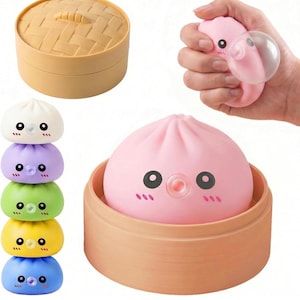 May include: A set of squishy dumpling toys featuring cute faces, including a pink dumpling inside a tan bamboo steamer basket, a closed steamer basket, and a vertical stack of five colorful dumplings in white, purple, green, yellow, and blue.