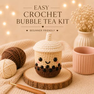 Peut inclure: Un kit de crochet de thé aux perles avec le texte "EASY CROCHET BUBBLE TEA KIT" et "BEGINNER FRIENDLY". Le kit comprend une tasse de thé aux perles crochetée beige et marron avec un visage souriant, des bobas noirs et un couvercle blanc. Le kit est sur une tranche de bois.