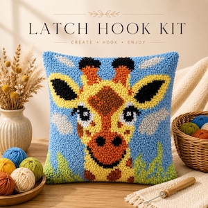 May include: A square latch hook kit pillow featuring a colorful giraffe design with a blue background. The text LATCH HOOK KIT CREATE HOOK ENJOY is visible at the top. The pillow displays a textured, tufted surface with yellow, orange, and black.