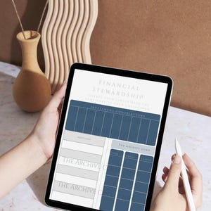 May include: A tablet displaying a financial stewardship template with sections for investment contributors and the archive fund. The tablet is held by hands, with a stylus nearby. The background includes a vase with dried flowers and a decorative wooden piece.