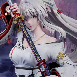 May include: A detailed anime-style figurine featuring a character with long white hair and red eyes. The figure wears a white kimono-inspired outfit with red accents and holds a decorative sword with a dark blade, gold details, and a red hilt.