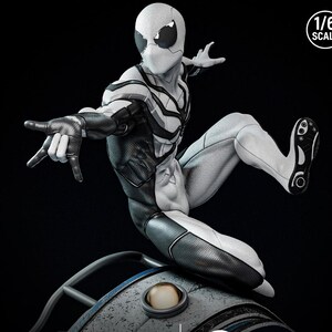 May include: A detailed, monochrome action figure of a superhero in a dynamic pose. The figure is predominantly white with black accents, including a mask, gloves, and sections of the suit. The figure is labeled as 1/6 scale.