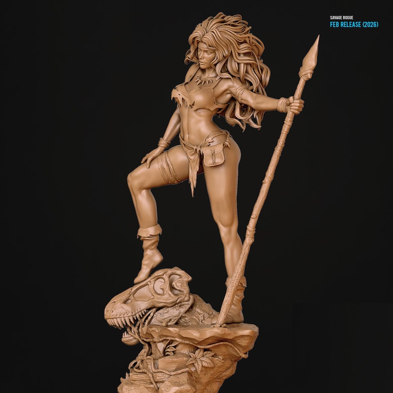 Op de afbeelding: Gedetailleerde bruine sculptuur van een vrouwelijke krijger met een speer, staand op een rotsformatie met een dinosaurus schedel. De tekst "SAVAGE ROGUE FEB RELEASE (2026)" is zichtbaar. Dynamische pose.