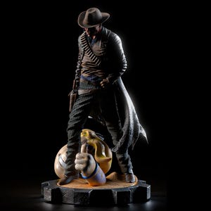 May include: A detailed figurine of a cowboy in a brown hat and duster coat, with a gun in a holster. The figure stands on a base with a thumbs-up hand and a money bag. The figure is in a dramatic pose, with a dark background.